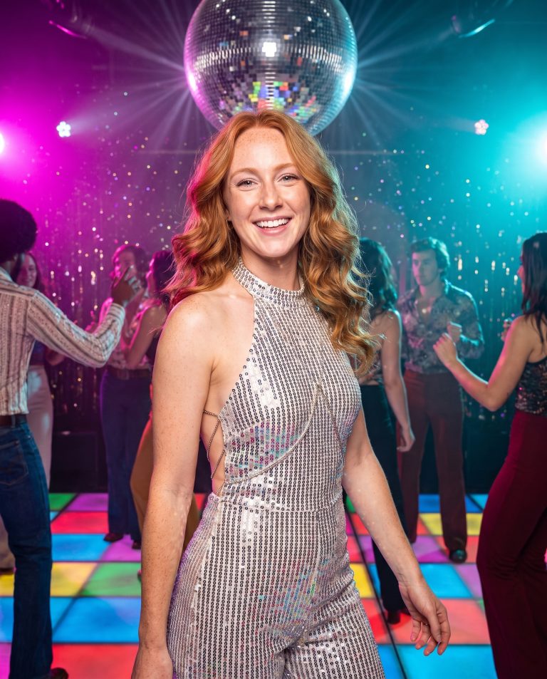 A guest is on a packed 1970s nightclub dance floor at peak hour.