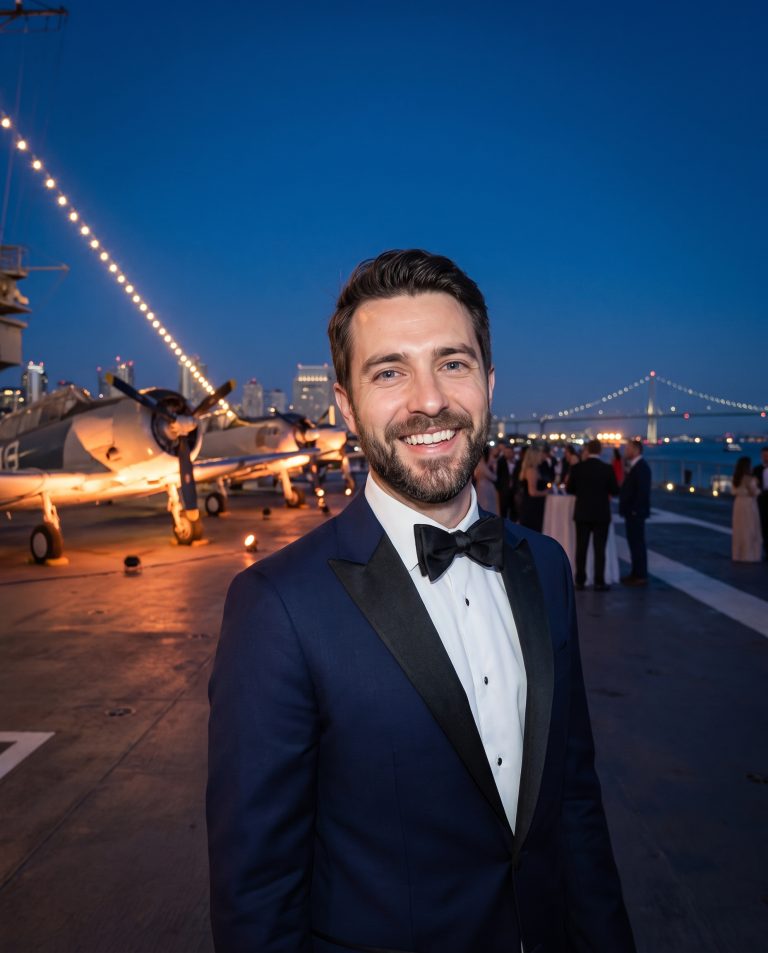A guest stands on the flight deck of a permanently berthed aircraft carrier at night, dressed for a black-tie gala.