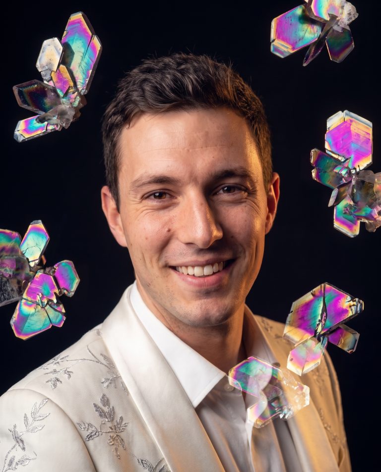 A guest is framed within a bloom of polarized-light crystal structures.