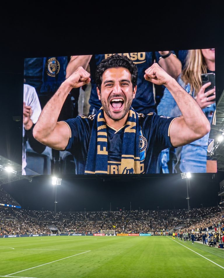 A guest appears larger than life on a giant stadium video board at night.