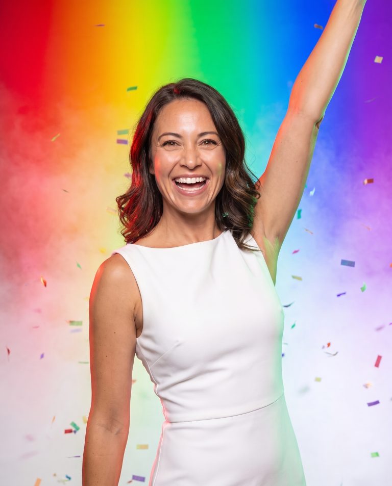 A guest in a bright studio flooded with broad bands of pure saturated color light sweeping across the frame.