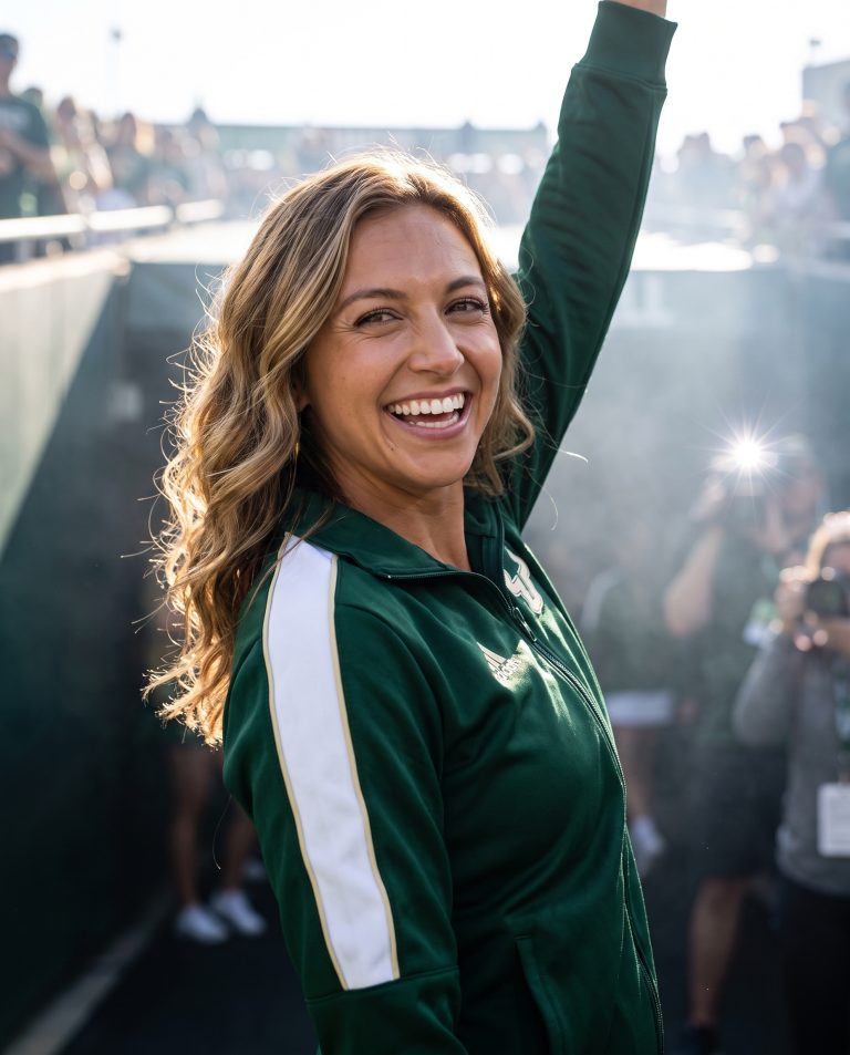 A guest strides out of a dark stadium tunnel into blazing daylight.