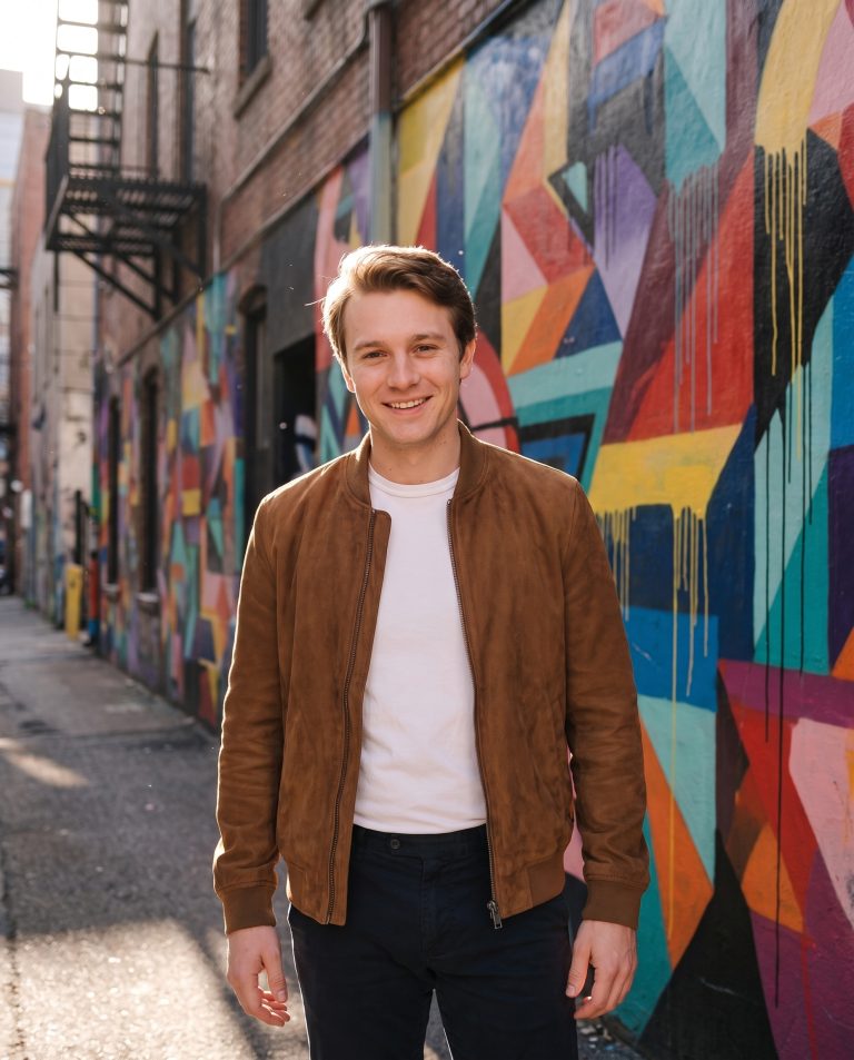 A guest in a narrow urban alley with both walls covered corner to corner in vivid original street art.