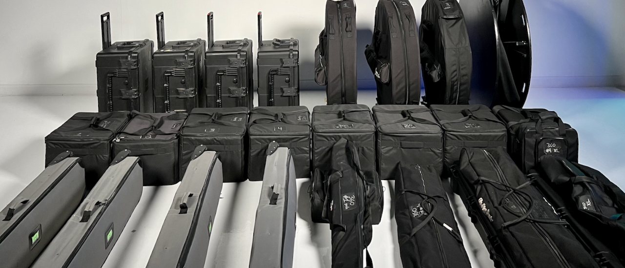 Rows of matching black road cases, camera bags and a 360 platform lined up on a studio floor