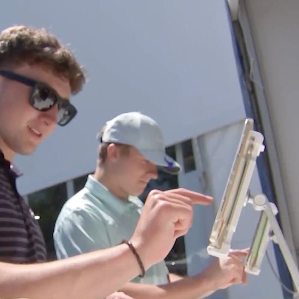 Two golf fans type their dog tag orders on touchscreens at an outdoor station