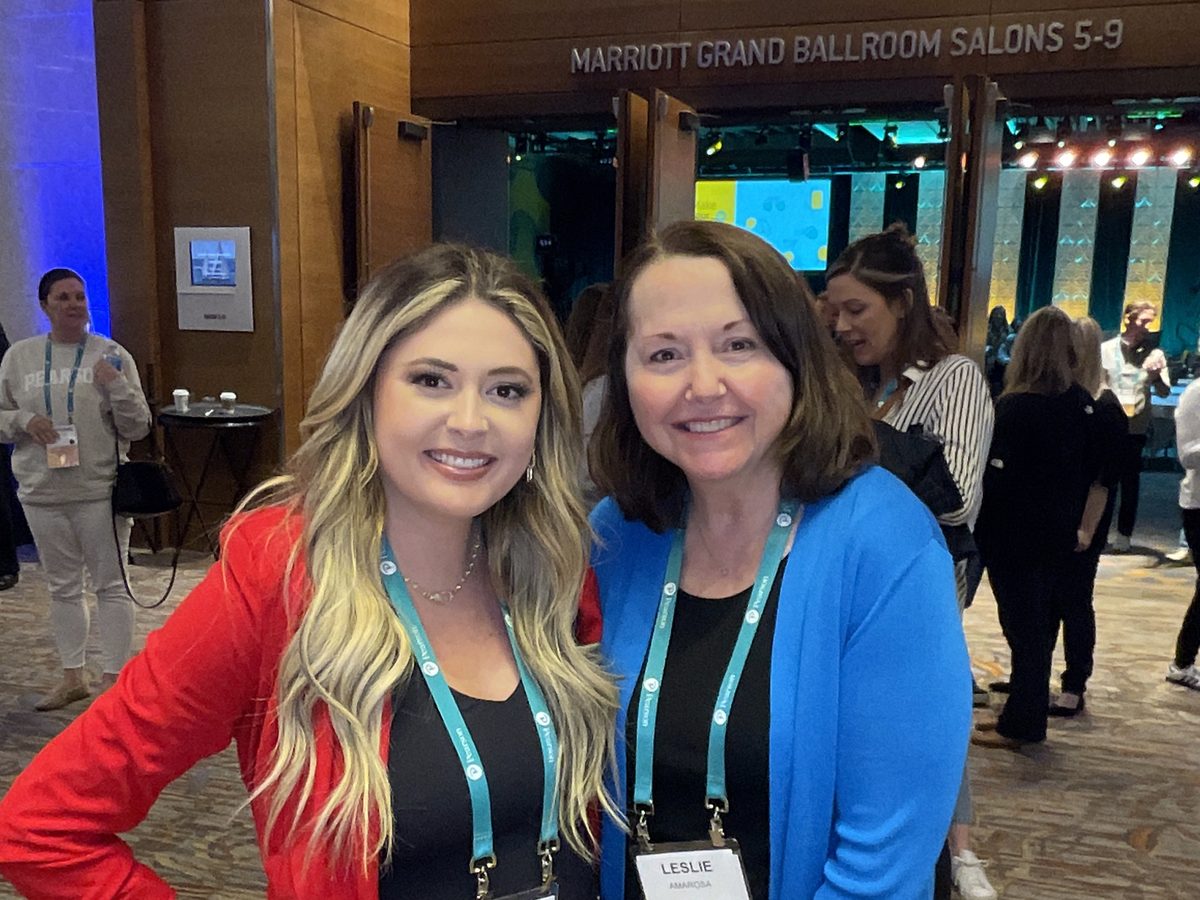 Two conference attendees outside the Marriott Grand Ballroom salons with the salon sign above the doors