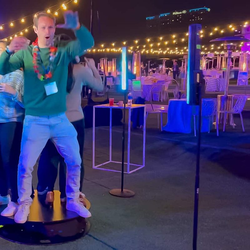 Guests posing on a 360 platform under string lights at an evening event at the Rady Shell