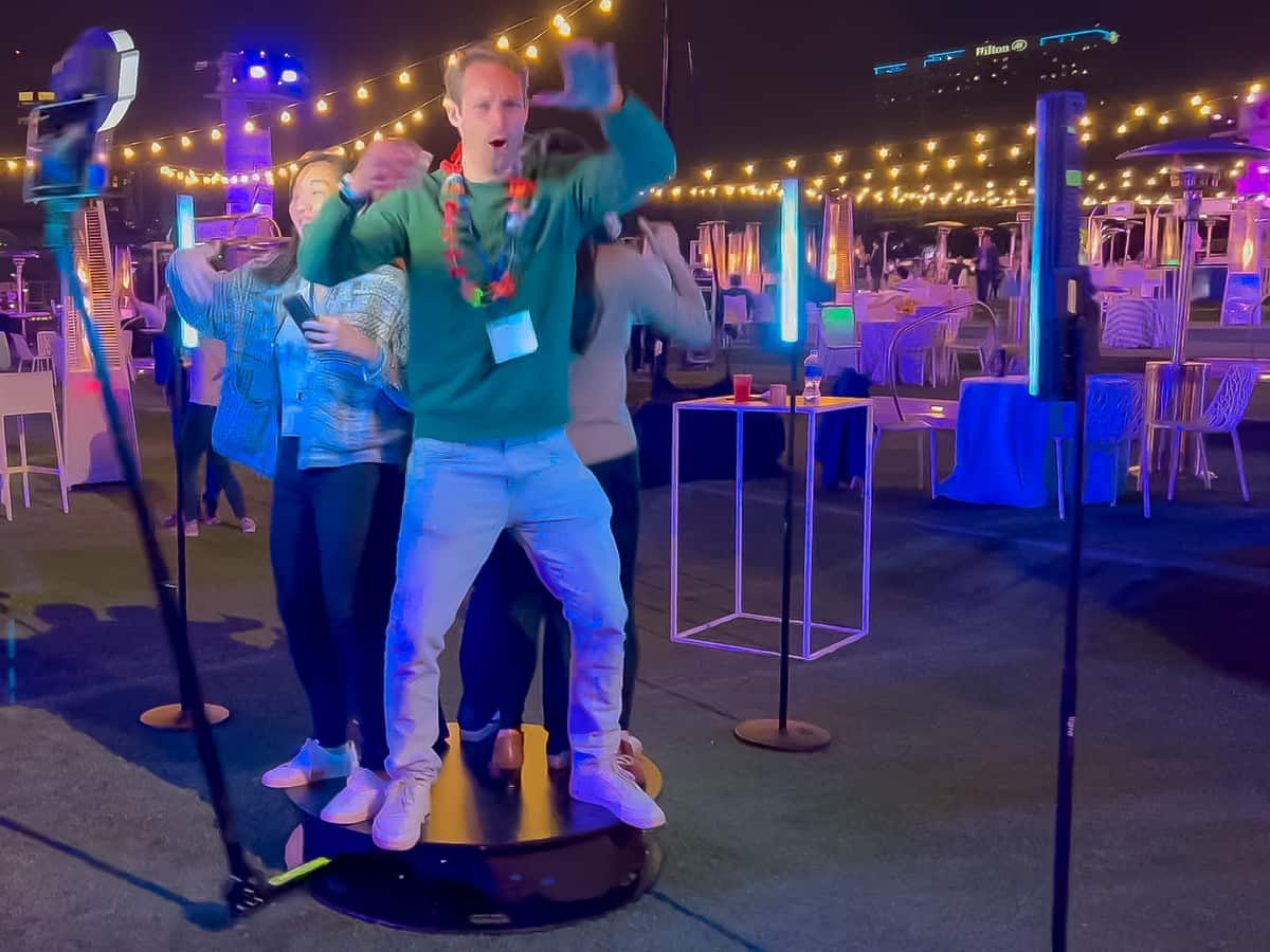 Guests posing on a 360 platform under string lights at an evening event at the Rady Shell